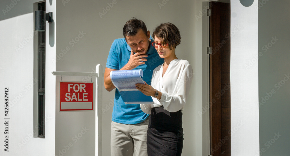 Beautiful woman realtor shows the house and drawings of the customer young man. Beautiful woman realtor shows the house and drawings of the customer young man.
