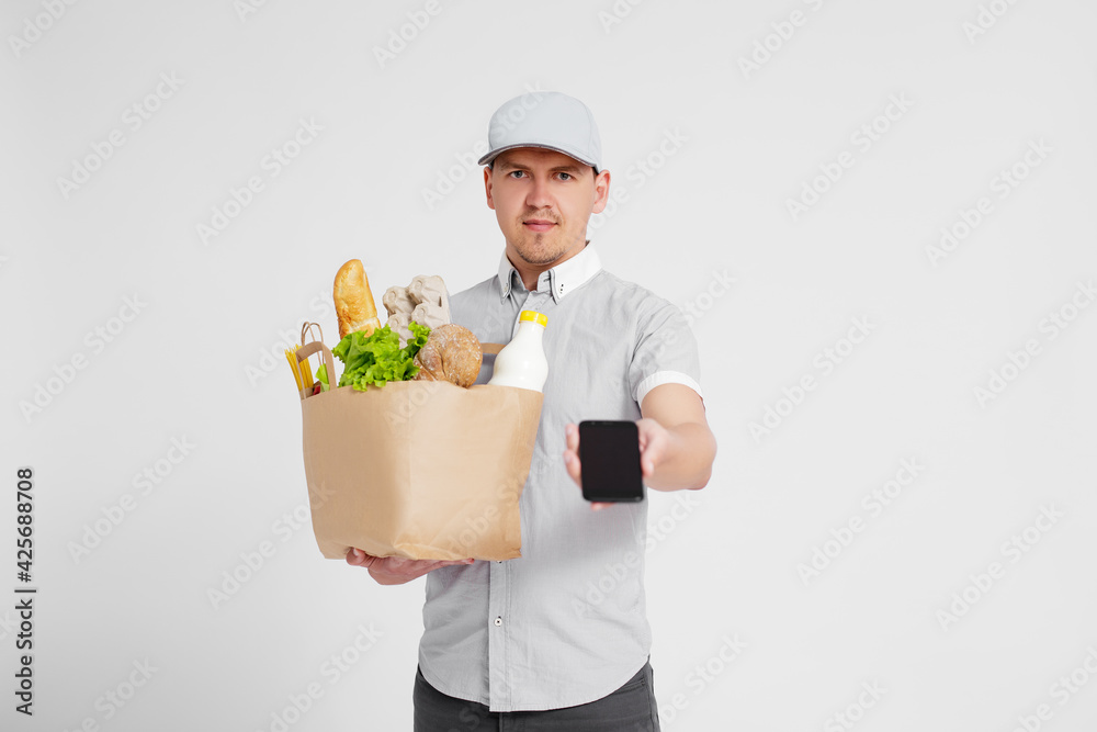 portrait of delivery man giving the paper bag full of products and asking for signature on the phone over white portrait of delivery man giving the paper bag full of products and asking for signature on the phone over white