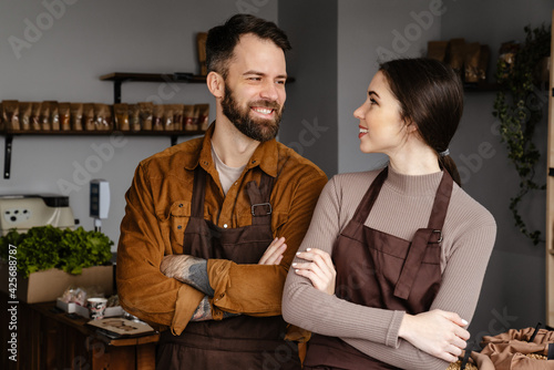 White sellers man and woman in aprons smiling at each other at local eco shop