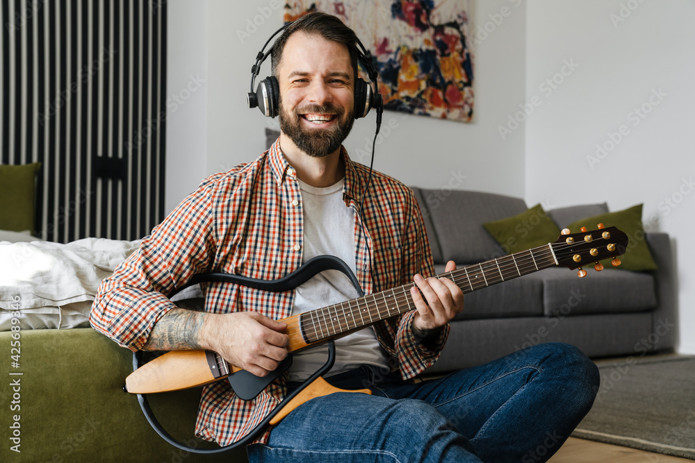 Obraz premium Smiling mid aged brunette bearded man playing