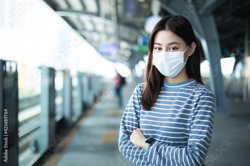 Young asian woman cover mouth , wear medical face mask to protect viruses.standing distance of 1 meter from other people keep distance protect from COVID-19 viruses.social distance.