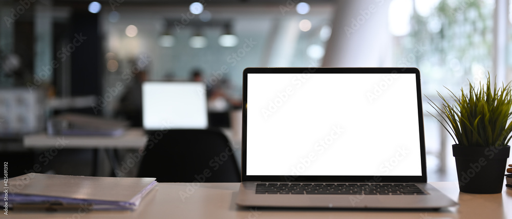 Front view of computer laptop and documents on white desk at modern office interior. Front view of computer laptop and documents on white desk at modern office interior.
