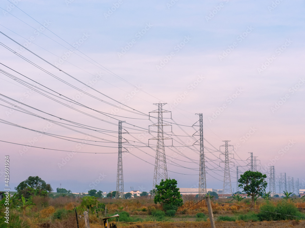 low of high voltage transmission towers with power line over twilight sky background the electricity infrastructure from power plant to industrial and household with morning dawn light