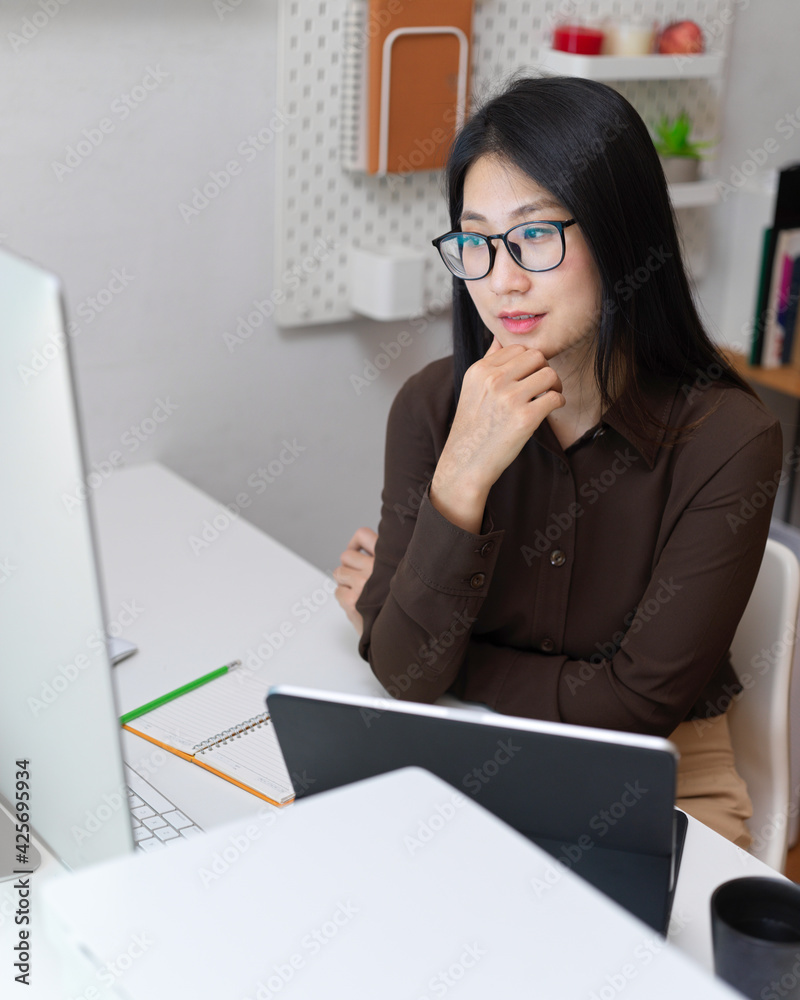 Female office worker considering about her work at office desk in office room Female office worker considering about her work at office desk in office room