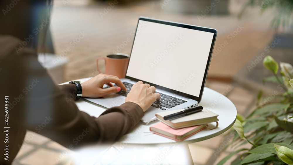 Female hands working with laptop on round table with supplies in cafe Female hands working with laptop on round table with supplies in cafe