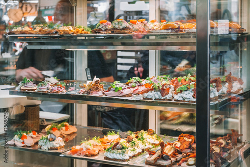 Copenhagen food market in Denmark. Danish smorrebrod traditional open sandwich at Copenhagen restaurant store. Many sandwiches on display with seafood and meat, smoked salmon, garnish, cold cuts. photo