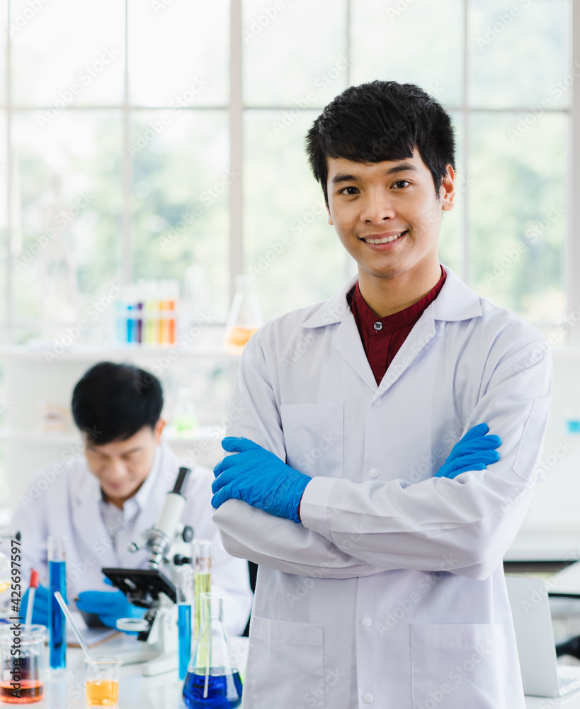 Portrait focus to young scientist asian man wearing uniform standing put hands in pocket and smiling feel happy and comfortable looking at camera in laboratory room. Portrait focus to young scientist asian man wearing uniform standing put hands in pocket and smiling feel happy and comfortable looking at camera in laboratory room.