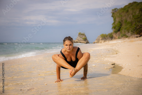 Caucasian woman practicing Bhujapidasana  Arm Pressure Balance on the beach. Strong healthy body. Self-care concept. Yoga retreat. Thomas beach  Bali