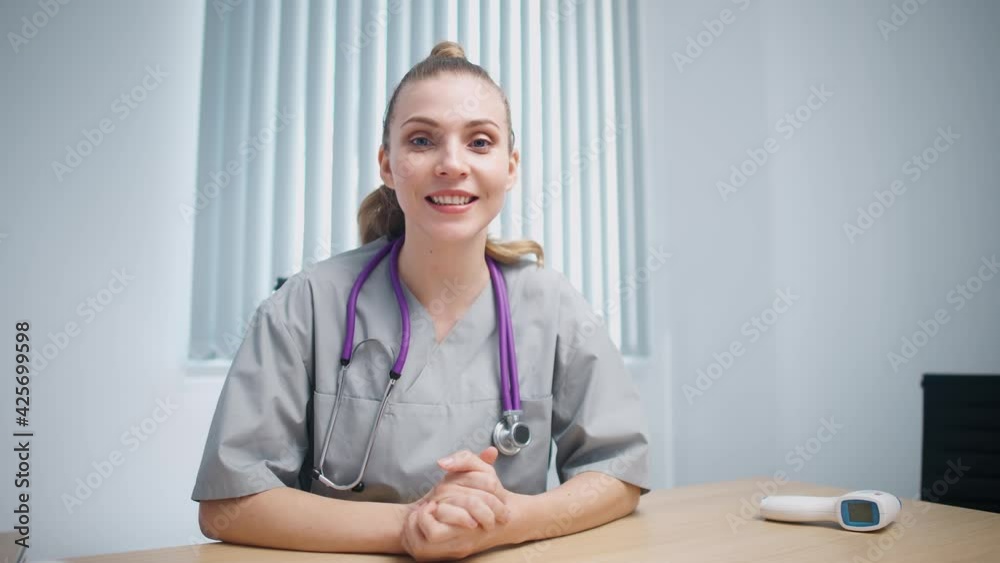 Woman doctor sits at workplace, looks at the camera and communicates with the patient via video call, remote conference of medical specialist and doctors online, modern hospital. Woman doctor sits at workplace, looks at the camera and communicates with the patient via video call, remote conference of medical specialist and doctors online, modern hospital.
