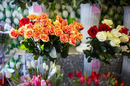 Fototapeta Naklejka Na Ścianę i Meble -  Blurred image of bouquet of fresh roses and tulips in flower shop. Lot of multicolored roses and tulips bouquets