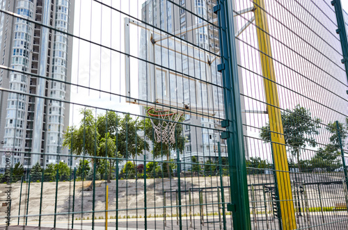 Basketball court from behind fence. Basketball hoop in the city park.  Selective focus, blurred background © supersomik