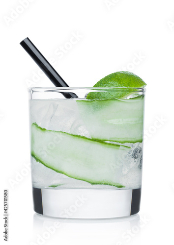Gimlet cocktail in glass with ice cubes and straw, cucumber and lime slice on white. © DenisMArt