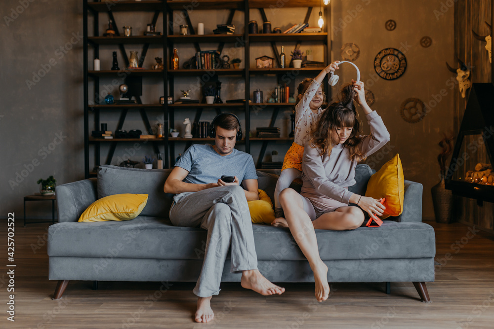 Husband and wife using gadgets ignoring kids. Man and woman addicted from smartphones. Couple on sofa with mobile phones. Husband and wife using gadgets ignoring kids. Man and woman addicted from smartphones. Couple on sofa with mobile phones.