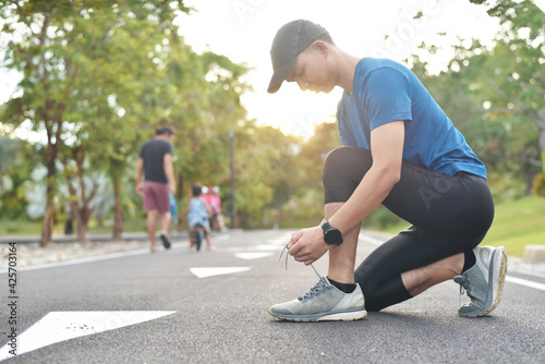 Young Asian man runner during wearing sports shoes and warm up before training