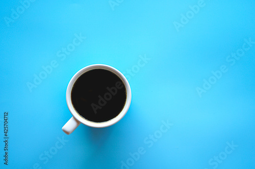 Flat lay of hot americano coffee in white coffee cup on blue background