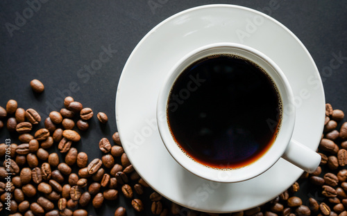 Cup of black coffee on black background with roasted coffee beans