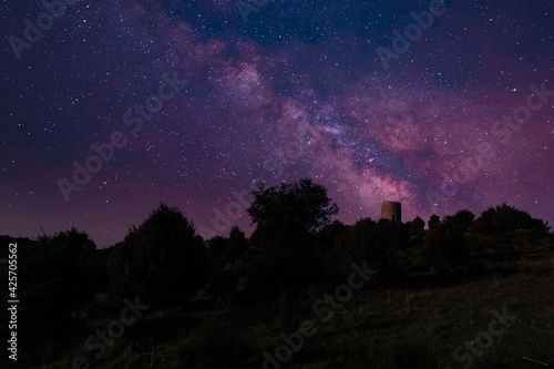milky way with a castle and silouete of the forest and trees