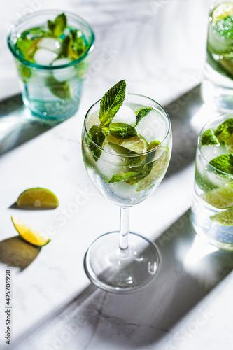 Mojito cocktail with mint and lime in glasses, white marble background. Refreshing drink with lime and mint in glasses.