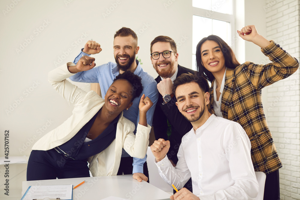 Multinational diverse happy creative business team raising fists making yes gesture celebrating victory feeling excited looking at camera. Win, success, unbelievable achievement and triumph concept Multinational diverse happy creative business team raising fists making yes gesture celebrating victory feeling excited looking at camera. Win, success, unbelievable achievement and triumph concept