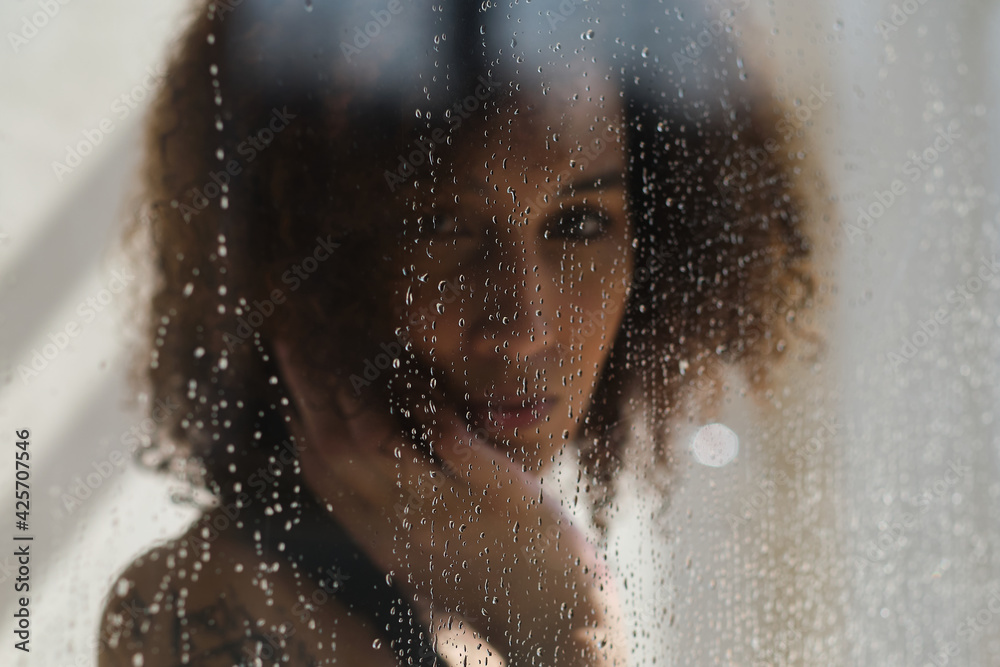 Defocused image of young female model poses in shower cabine. Peaceful woman. Soul healing. Spiritual practice. Esoteric mystery.