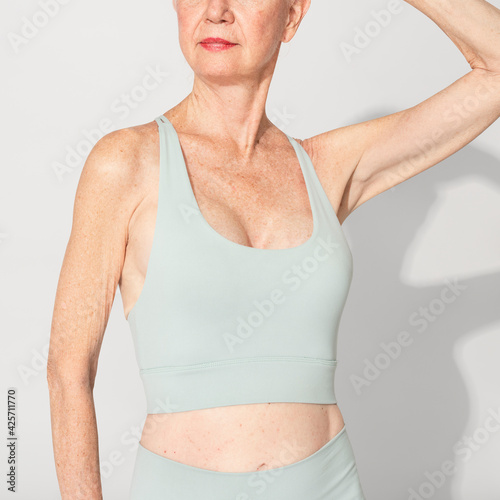 Healthy senior woman in mint green sports bra and leggings
