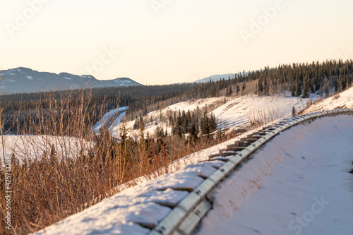 Wilderness road, highway in northern Canada with mountains surrounding with spruce trees. Road trip, drive, camping in spring time, winter. 