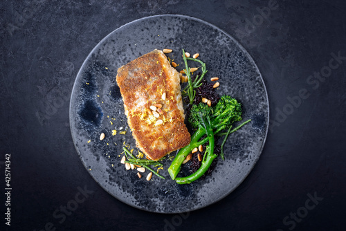 Photography Modern style traditional pan-fried skrei cod fish filet in breadcrumbs with baby