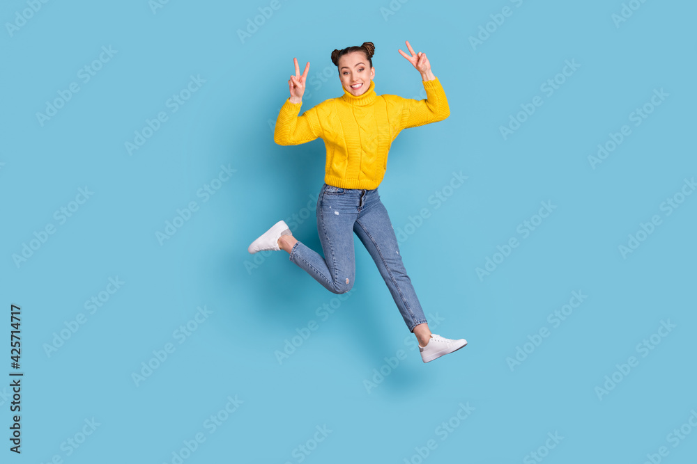 Full length body size view of attractive funny cheerful girl jumping showing v-sign isolated over vibrant blue color background