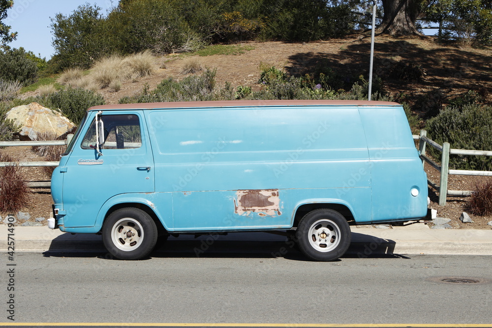 Old Faded Blue van parked on street with rust spot