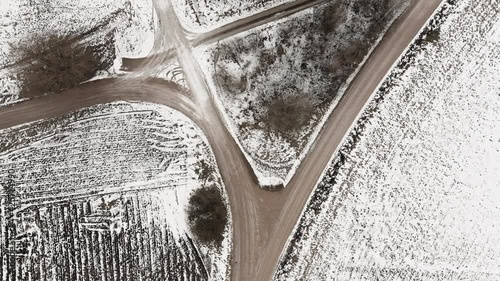 Aerial view with countryside road and snow covered plowed agriculture fields