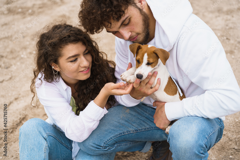 Guy with girl playing with doggy on beach Guy with girl playing with doggy on beach