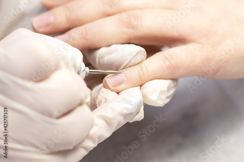 Manicure hand nail care with special tools in a beauty salon by a manicure specialist. Close-up. Space for the text.