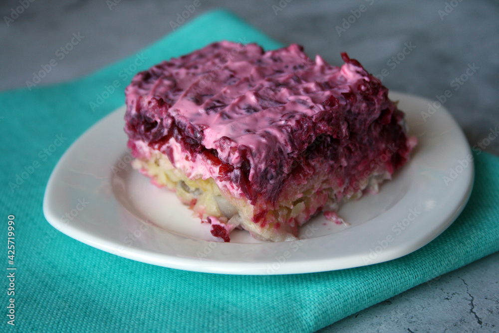 Layered salad of herring, potatoes and beets with mayonnaise in a white plate. Layered salad of herring, potatoes and beets with mayonnaise in a white plate.