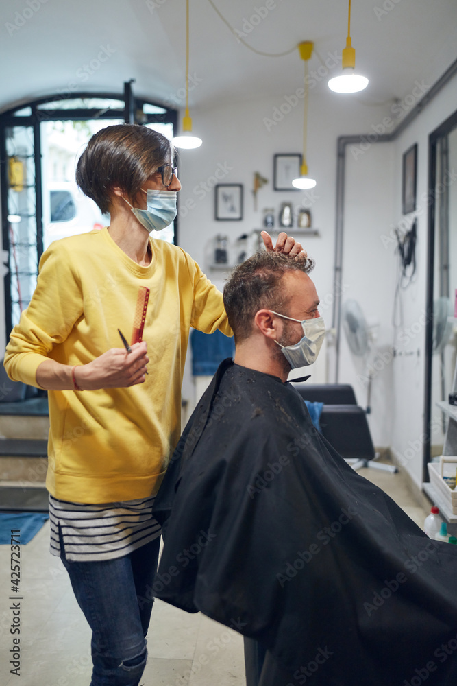 Hairdresser and customer in a salon with medical masks during virus pandemic. Working with safety mask. Hairdresser and customer in a salon with medical masks during virus pandemic. Working with safety mask.