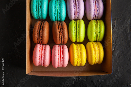 colored fresh macarons in the studio on a black background in a box