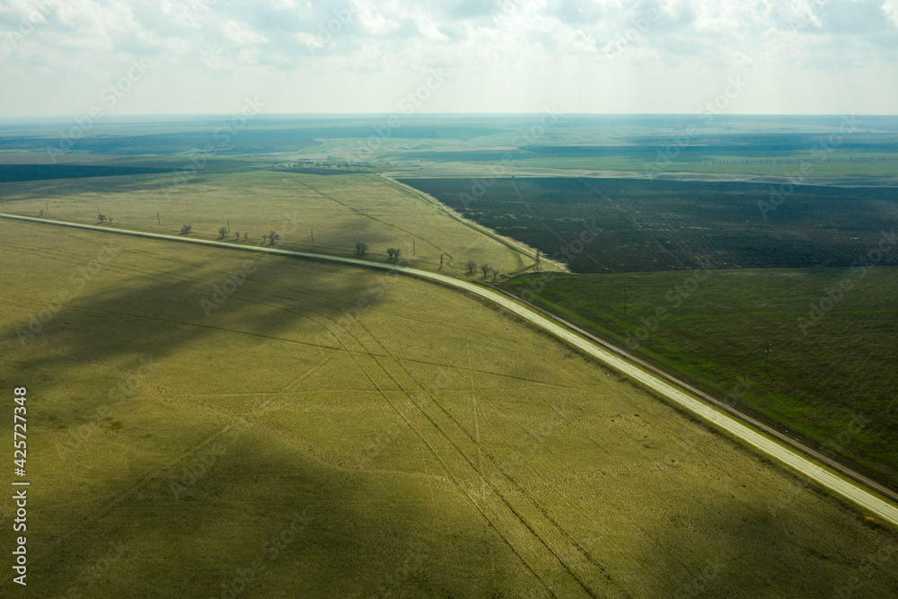 a wedge of arable land among fields and a highway spring landscape shooting from a drone