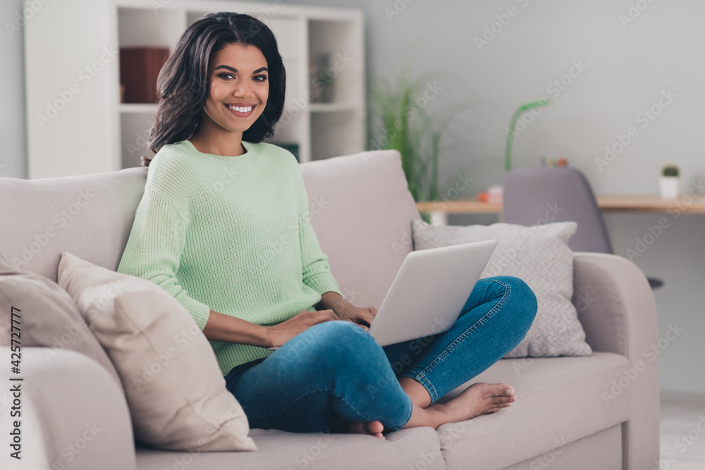 Full body photo of young attractive afro woman happy positive smile sit couch browse laptop chat type email indoors Full body photo of young attractive afro woman happy positive smile sit couch browse laptop chat type email indoors