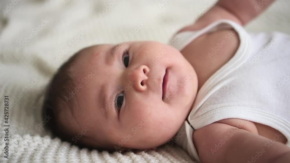 Closeup view of small baby lying and moving his hands on bed in home bedroom spbd. Closeup view of small baby lying and moving his hands on bed in home bedroom spbd.