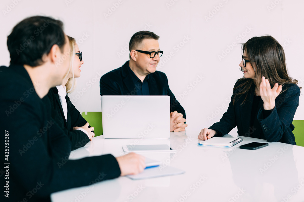 Working together. Group of young business people discussing business and smiling while sitting in the creative office Working together. Group of young business people discussing business and smiling while sitting in the creative office