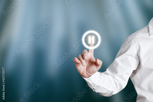 Male hand presses pause icon on a virtual display screen. photo