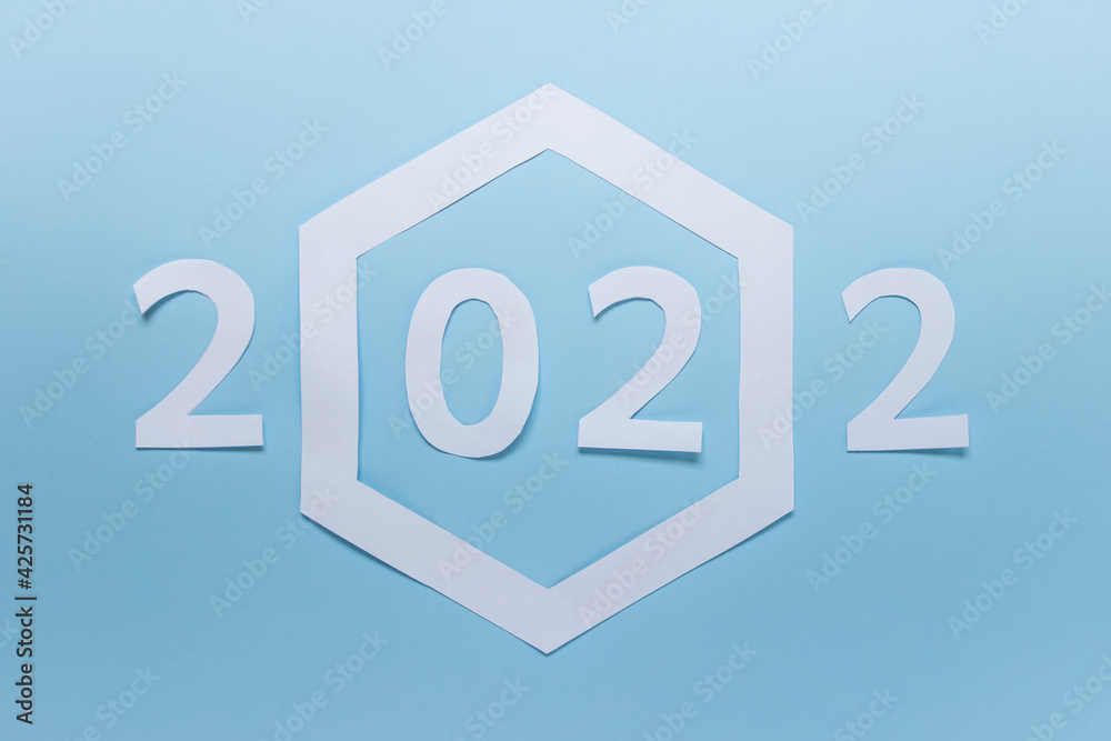 New year 2022 made of paper with large paper hexagon on blue background.