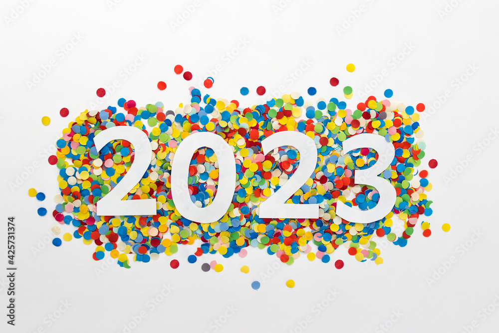 New year 2023 number made of white paper arranged on colorful confetti on white paper. New year 2023 number made of white paper arranged on colorful confetti on white paper.