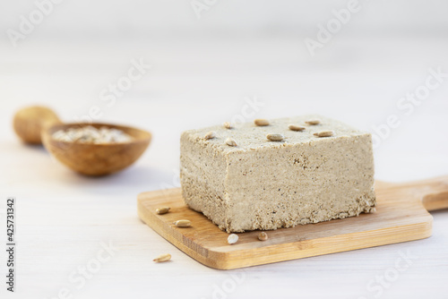 Halva with sunflower seeds on a wooden board.
