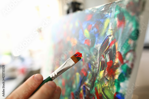 Fotografie Hand holds brush with watercolors and paints picture