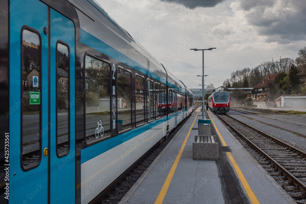 Old versus new passenger train standing on a platform. Concept of modernisation of rolling stock on railways. Old versus new passenger train standing on a platform. Concept of modernisation of rolling stock on railways.