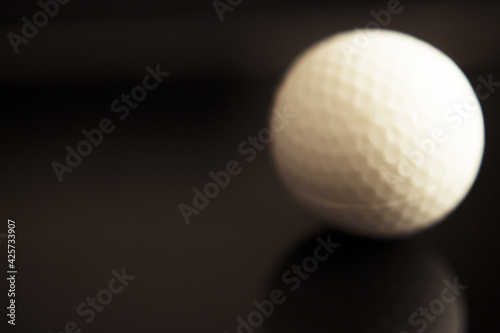 White golf ball somewhat out of focus on dark background