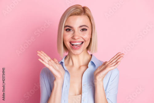 Photo of cheerful pretty nice young woman raise hands palms smile excited isolated on pink color background