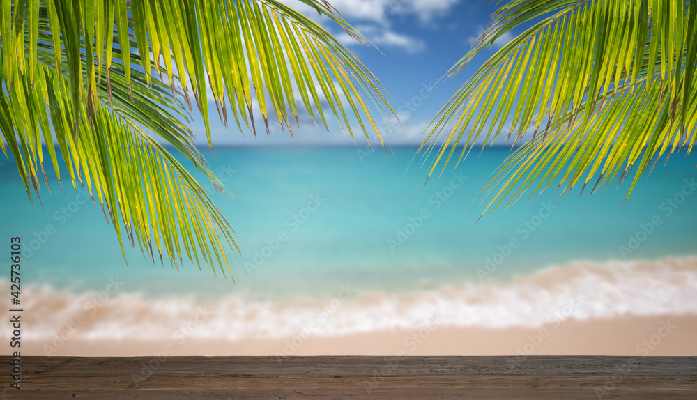 Wooden table and palm leaves in front of blurred tropical sea background.