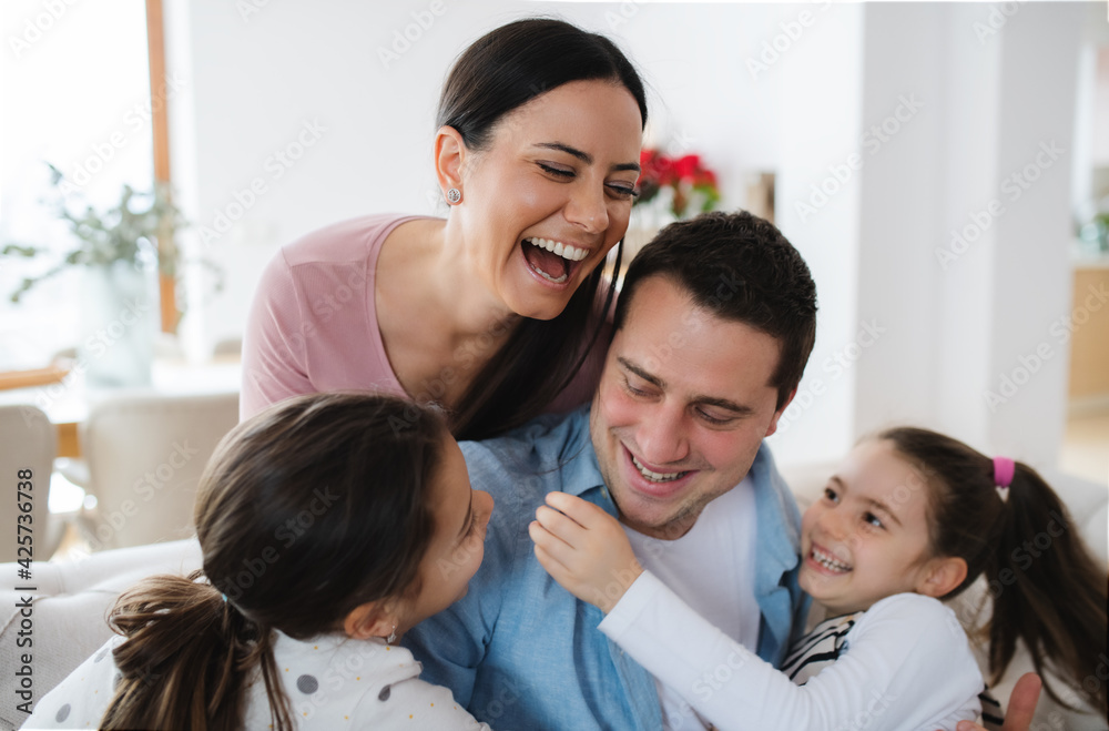 Cheerful parents with small daughters indoors at home, having fun. Cheerful parents with small daughters indoors at home, having fun.