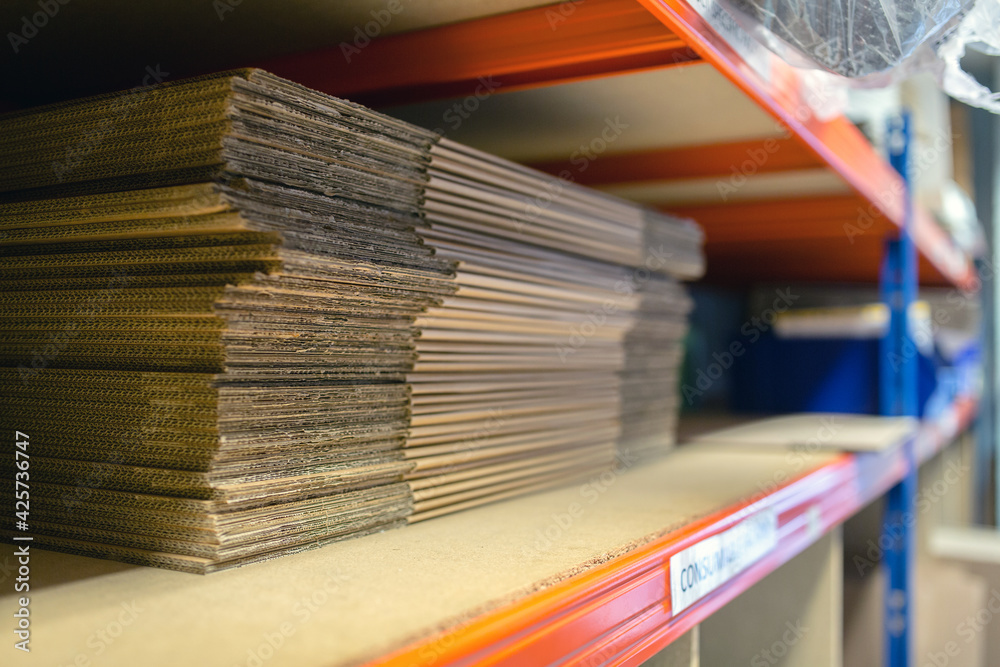 Fototapeta premium A selection of flat shipping boxes/cartons on a shelf ready to be made up and packed with product. Warehouse, despatch, shipping, parcel concept